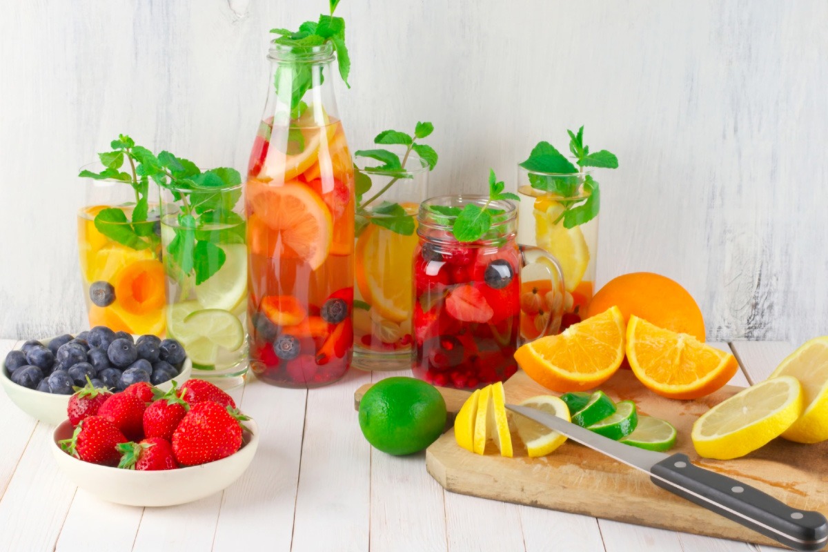 idratazione i consigli di beauty Med un tavola riccamente imbandita e colorata con frutta anche tagliata a spicchi e bicchieri e bottiglie con liquidi idratanti e rinfrescanti